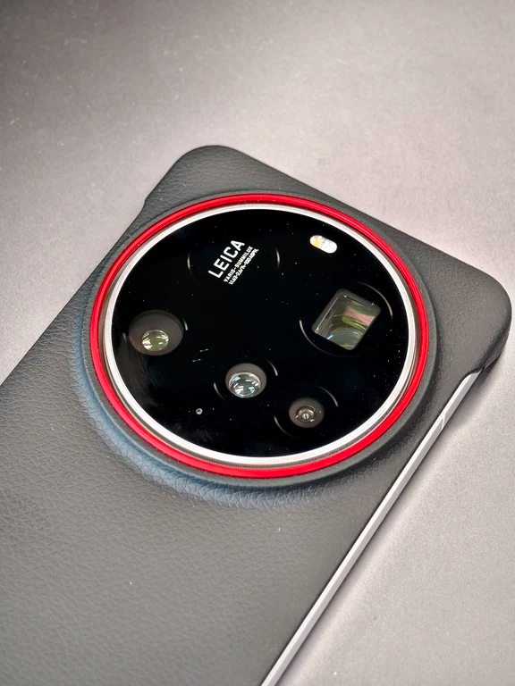 Close-up of a circular multi-lens camera module with a prominent red metal accent ring