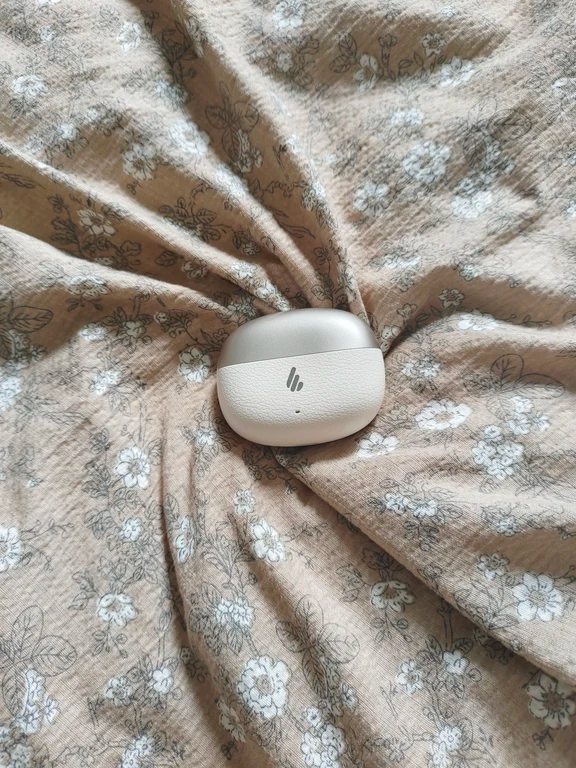 Compact Edifier charging case in a cream and champagne leather-textured finish on floral fabric