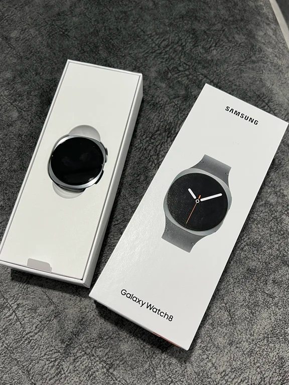 Samsung Galaxy Watch 8 in open retail packaging showing the watch body and branded box