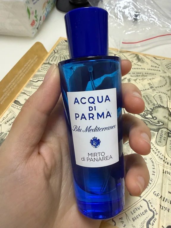 Hand holding a blue glass bottle of Acqua di Parma Mirto di Panarea eau de toilette