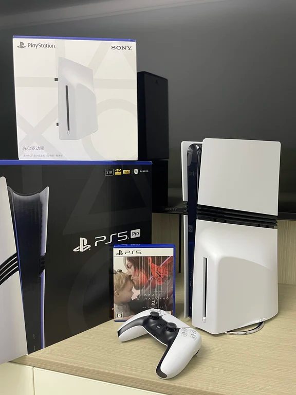 PlayStation 5 Pro retail box shown with a detachable disc drive box, standing console, and a DualSense controller next to a Death Stranding 2 case.