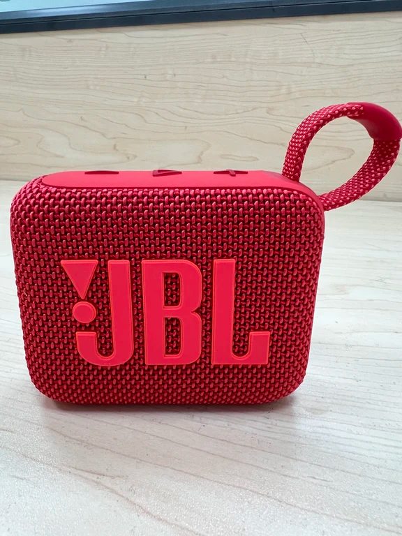 Red JBL GO 4 ultra-portable Bluetooth speaker with fabric grille, embossed JBL logo, and integrated loop.
