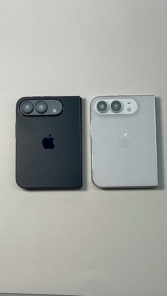 Folded dark blue and starlight white foldable smartphone models resting side by side on a flat desk