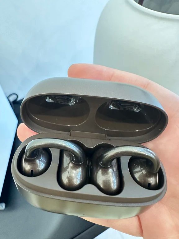 Close-up of metallic-finish ear-clip wireless earphones seated in an open case.