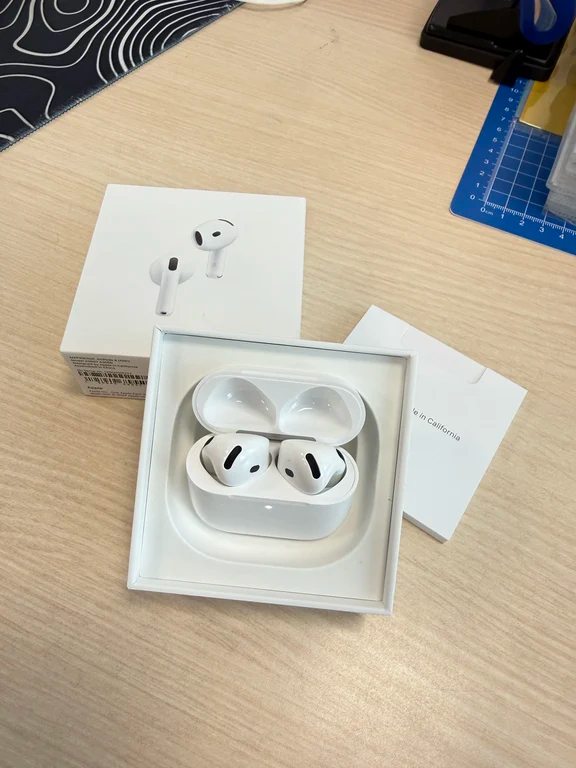 Open packaging box showing Apple AirPods 4 earbuds inside their white charging case