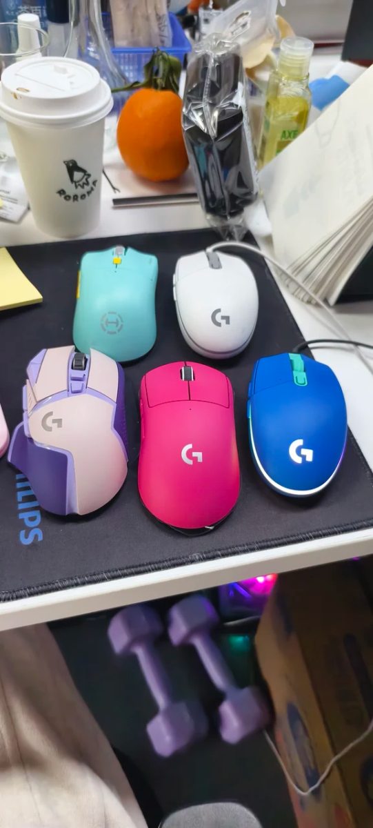 Desk mat featuring several colorful gaming mice including pink and blue Logitech models