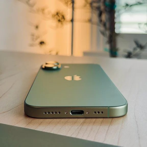 Close-up of a green iPhone on a wooden surface with design features