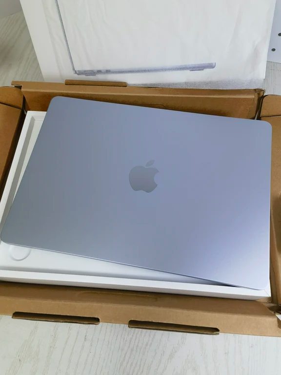 Top-down view of an open retail box containing a light blue Apple MacBook Air laptop