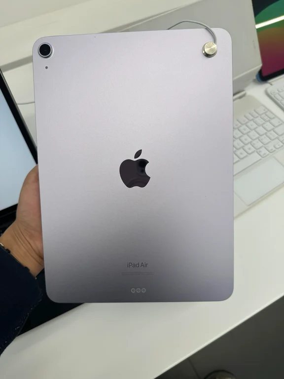 Hand holding a light purple iPad Air showing its rear camera and logo