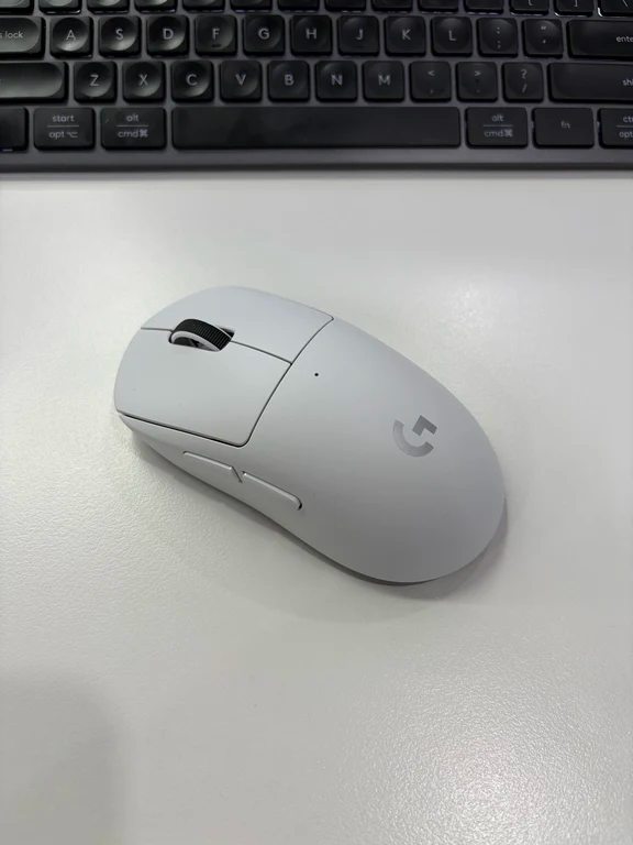 White Logitech G Pro X Superlight wireless gaming mouse on a white desk next to a keyboard