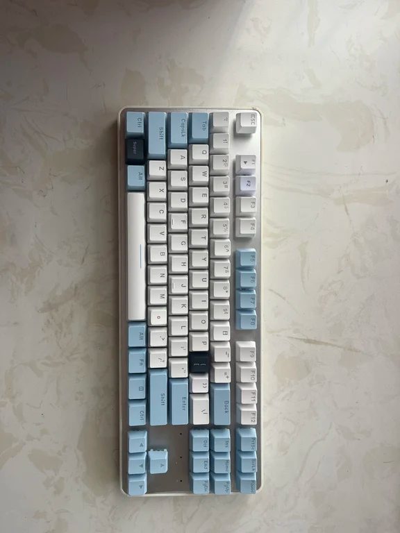 Compact mechanical keyboard with light blue and white keycaps on a light background
