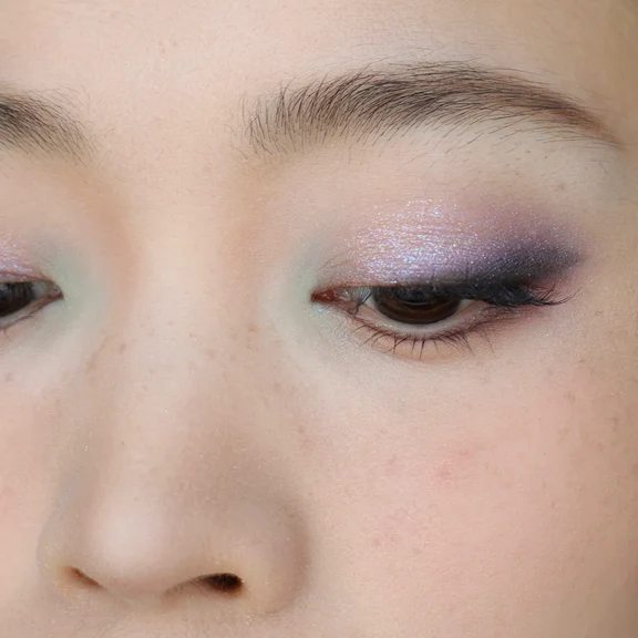 Close-up of eye makeup featuring blended purple shimmer and light pastel eyeshadow tones