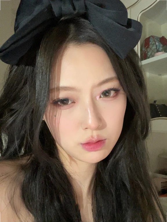 Woman with soft glam eye makeup, subtle pink lips, and a large black hair bow