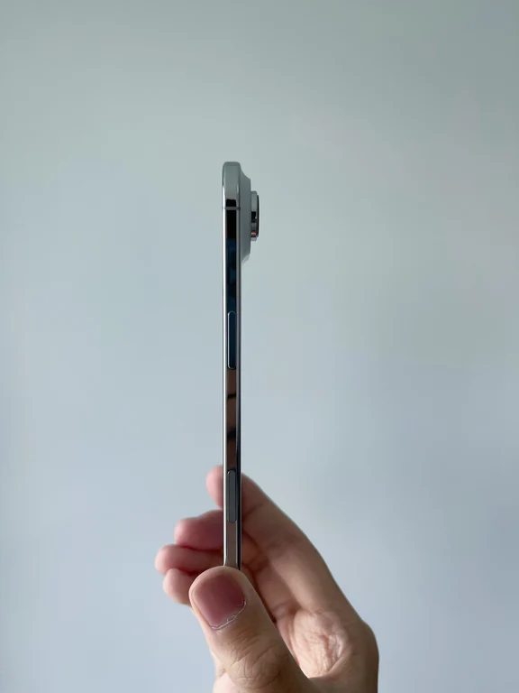 Profile side view of an ultra-thin smartphone held in hand showing the slim metallic edge and rear camera protrusion.