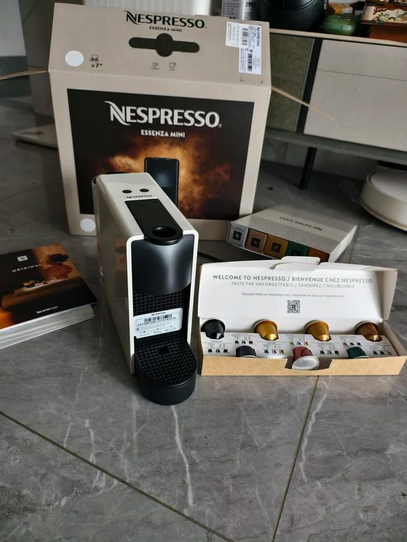 Unboxed white Nespresso Essenza Mini capsule coffee machine with packaging box and coffee pods