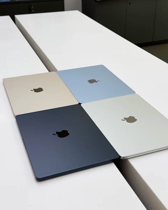 Four Apple MacBook Air laptops arranged in a square showing starlight, light blue, midnight, and silver lid colors