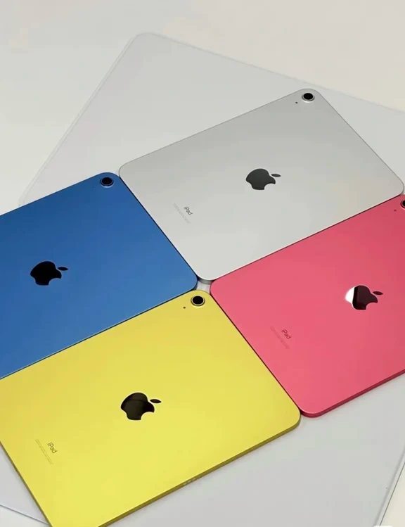 Four Apple iPad tablets in silver, blue, yellow, and pink colors displayed back-side up.