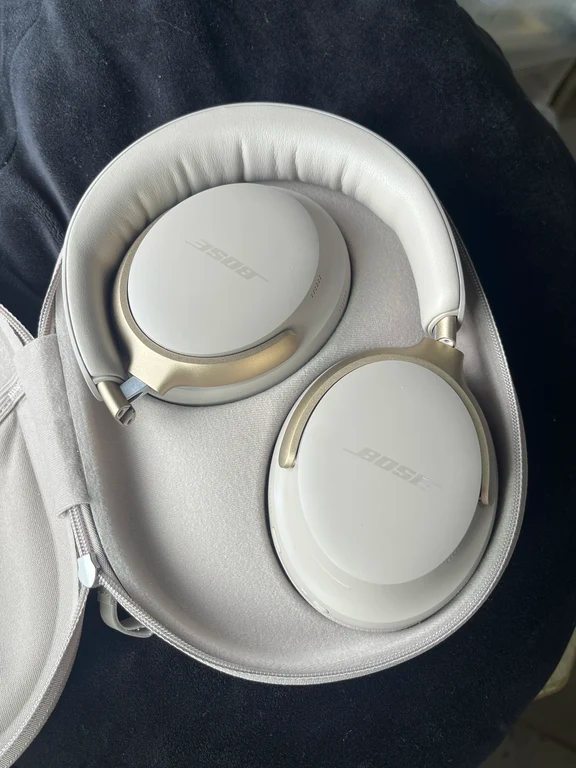 Bose QuietComfort Ultra headphones resting folded inside an open grey carrying pouch.