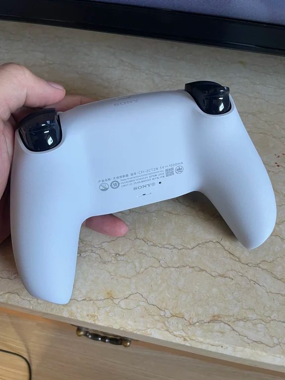 Rear view of a white PS5 DualSense controller showing Sony model text and grips