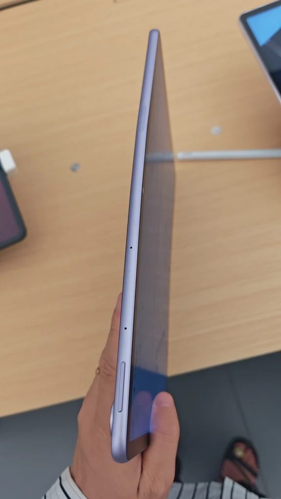 Side profile view showing the slim edge and buttons of a tablet held in hand.