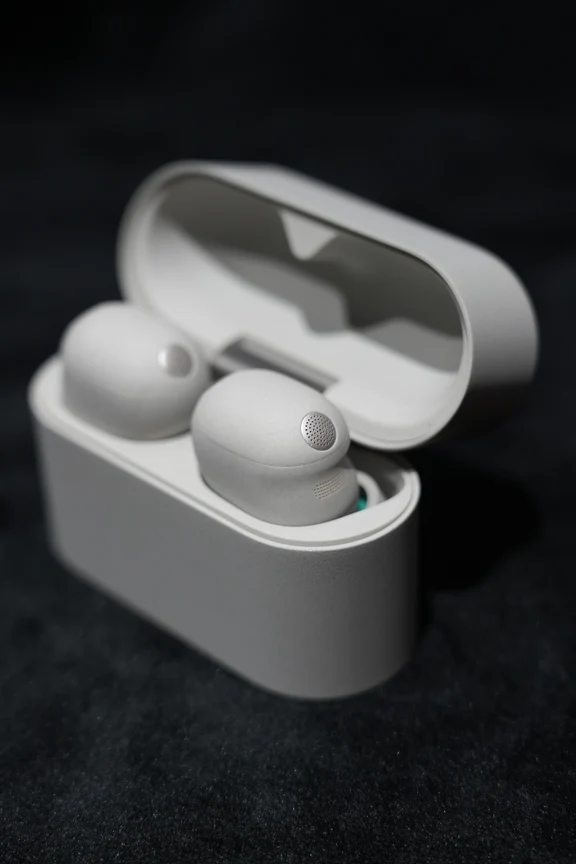 Sony beige true wireless earbuds resting inside their open oval charging case