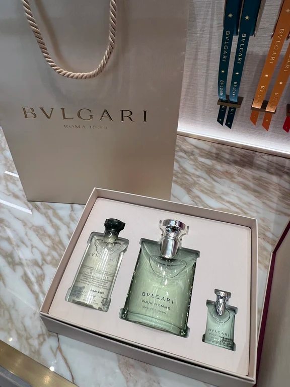 A Bvlgari Pour Homme gift set box featuring a full perfume bottle, mini travel bottle, and lotion beside a gift bag.