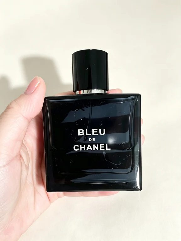 يد تمسك بزجاجة عطر بلو دي شانيل المربعة الداكنة
