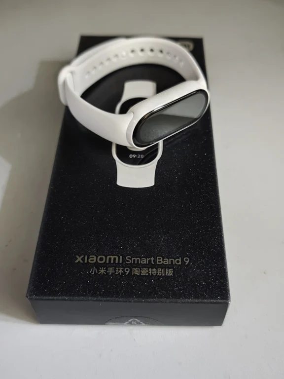 Xiaomi Smart Band 9 Ceramic Edition featuring a white ceramic strap and body sitting on top of its black package box