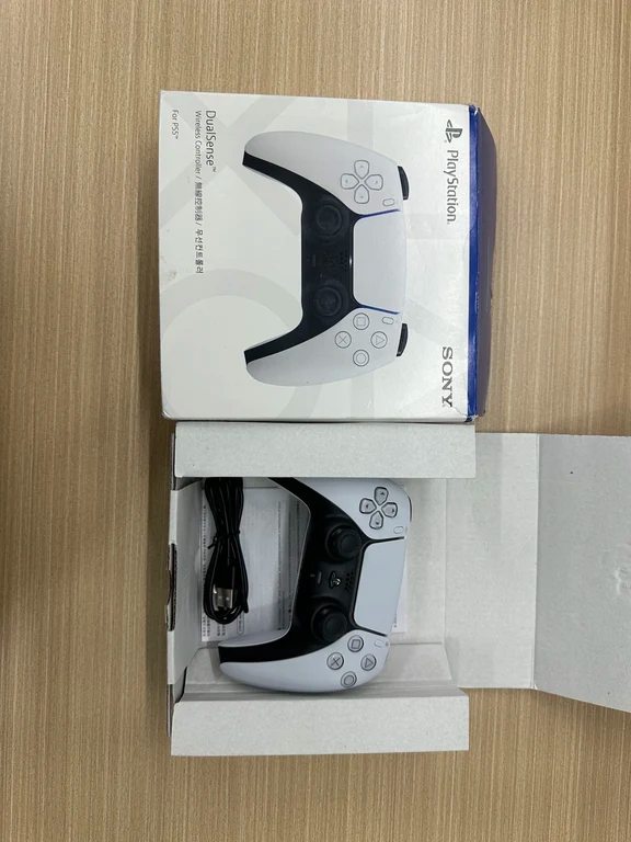 Sony PS5 DualSense controller in white placed next to its official retail packaging