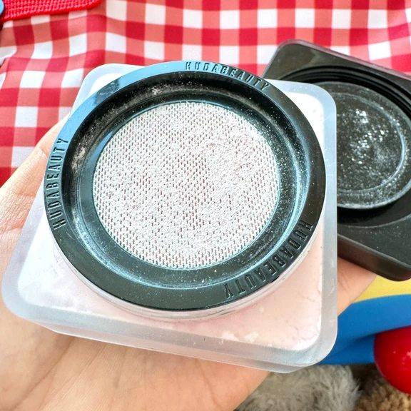 Top view of the interior mesh sifter inside a Huda Beauty loose setting powder jar