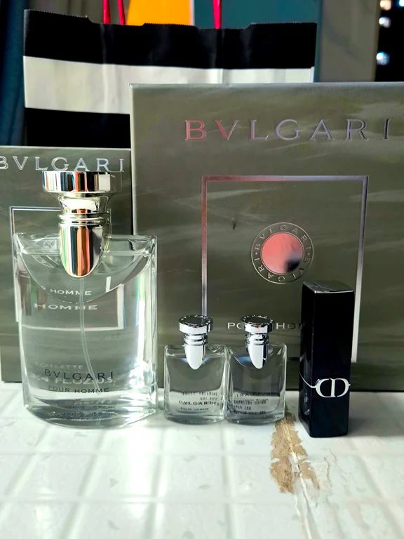 A clear Bvlgari Pour Homme eau de toilette bottle displayed next to two miniature dab bottles and a small cosmetic stick.