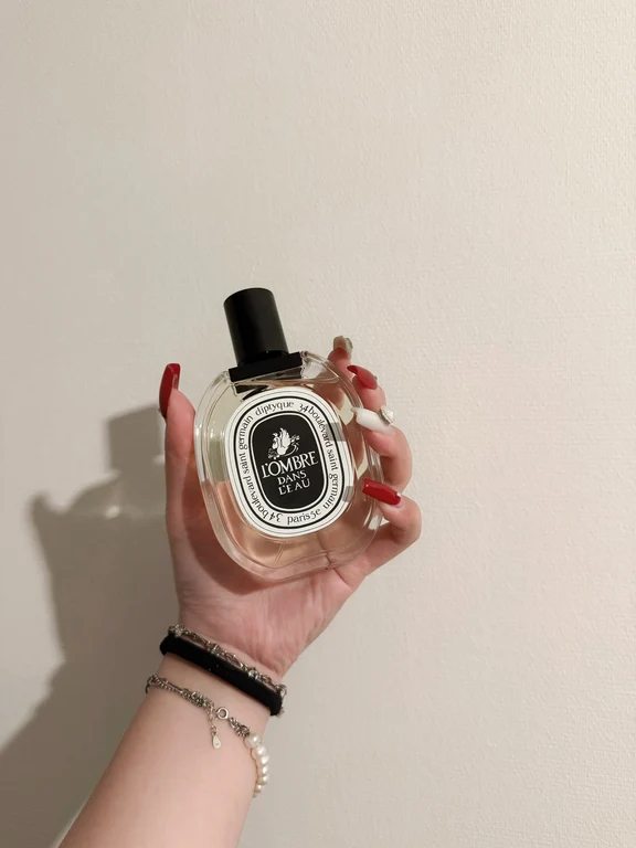 Hand holding a bottle of Diptyque L'Ombre Dans L'Eau eau de parfum