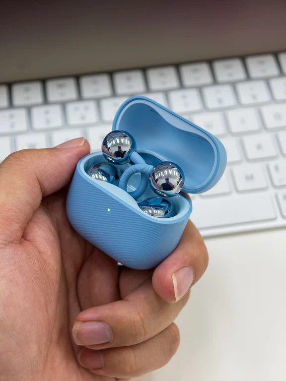 Light blue open charging case held in a hand showing clip-on sports earbuds inside