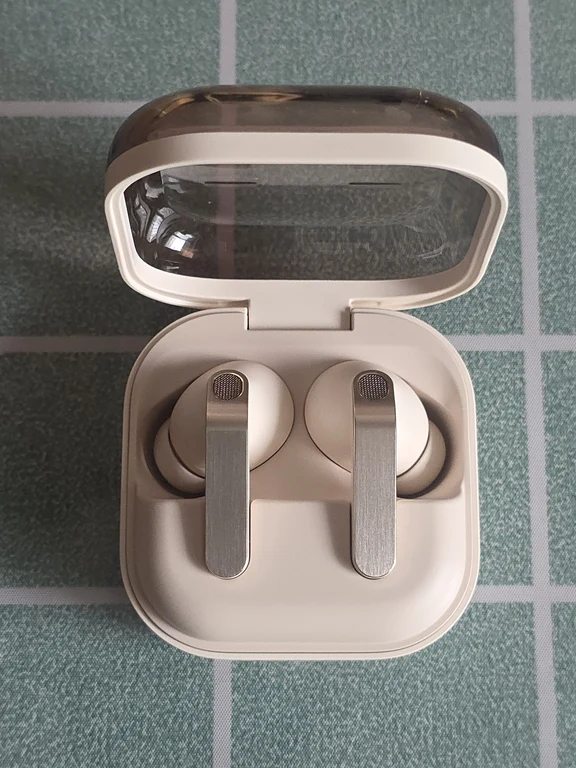 Open square charging case showing two white in-ear wireless earphones with silver stems