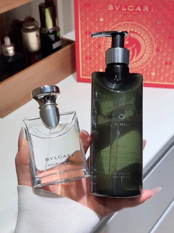 يد تحمل زجاجة عطر بولغاري بور هوم إلى جانب عبوة جل الاستحمام من نفس المجموعة