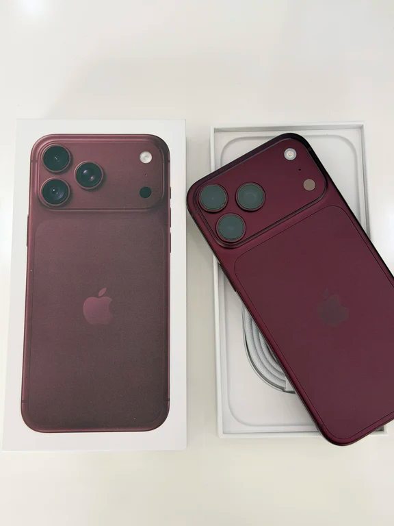 Burgundy concept smartphone lying on its open retail box with an included white charging cable