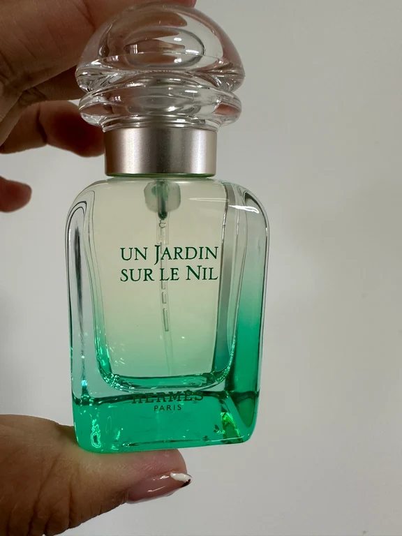 لقطة مقربة لزجاجة عطر إيرميس أن جاردان سور لو نيل باللون الأخضر الفاتح في اليد