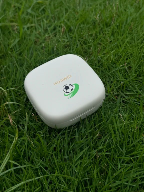 White square Huawei earbud case resting on green outdoor grass